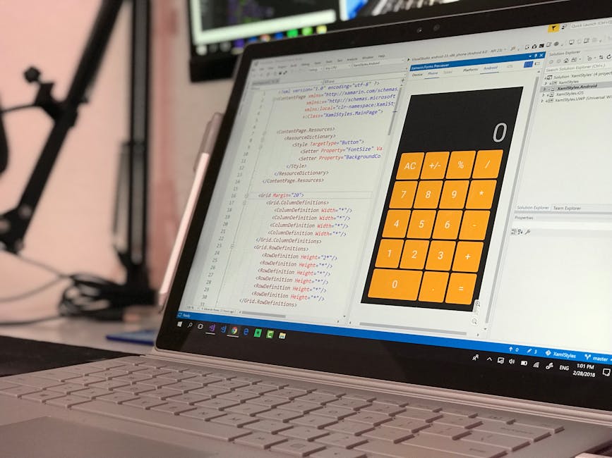 Close-up of a laptop screen displaying lines of code on the left side and a digital calculator interface with orange buttons on the right side, set on a desk in an office environment. The code include